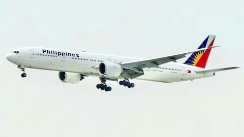 Philippine Airlines Boeing 777 flying with its landing gear lowered against a clear sky
