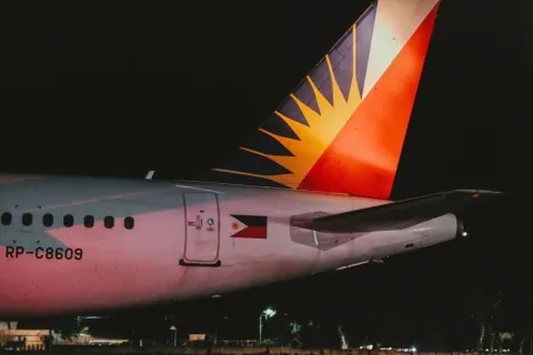 Philippine Airlines aircraft tail fin lit up at night on the runway